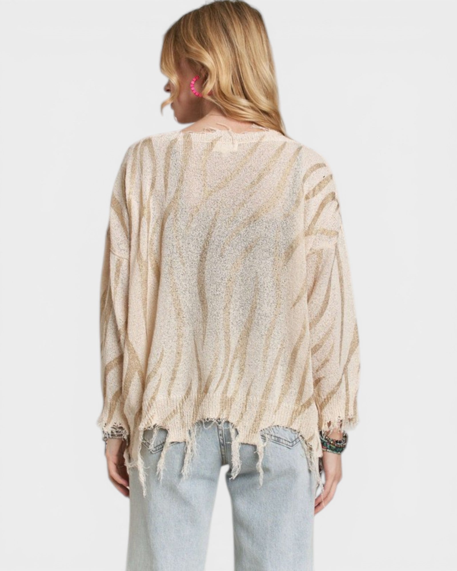 Person wearing a beige and brown striped sweater with a plain background