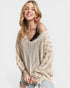 Woman wearing a beige off-shoulder sweater with a plain background