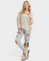 Woman wearing a beige sweater and ripped jeans on a white background