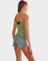 Woman wearing a green crochet top and denim shorts on a white background