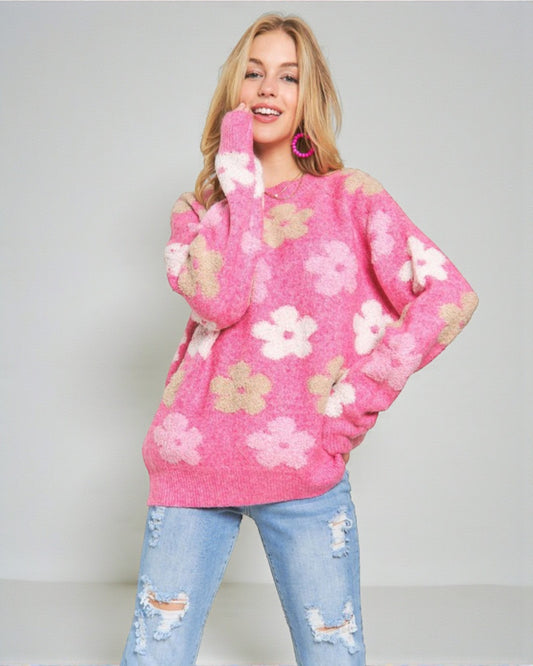 Woman wearing a pink floral sweater and light blue jeans on a plain background