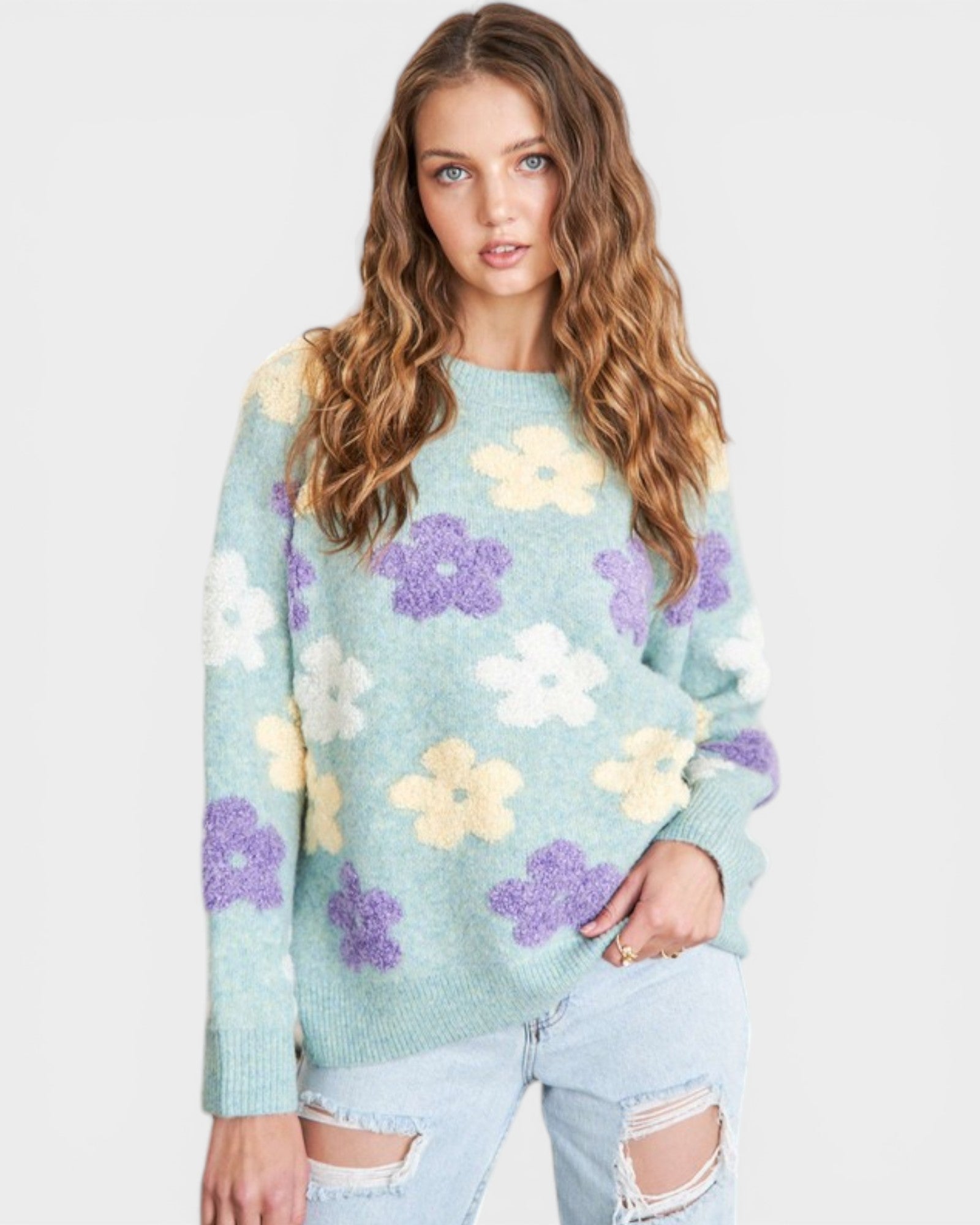 Woman wearing a light blue sweater with floral patterns on a white background