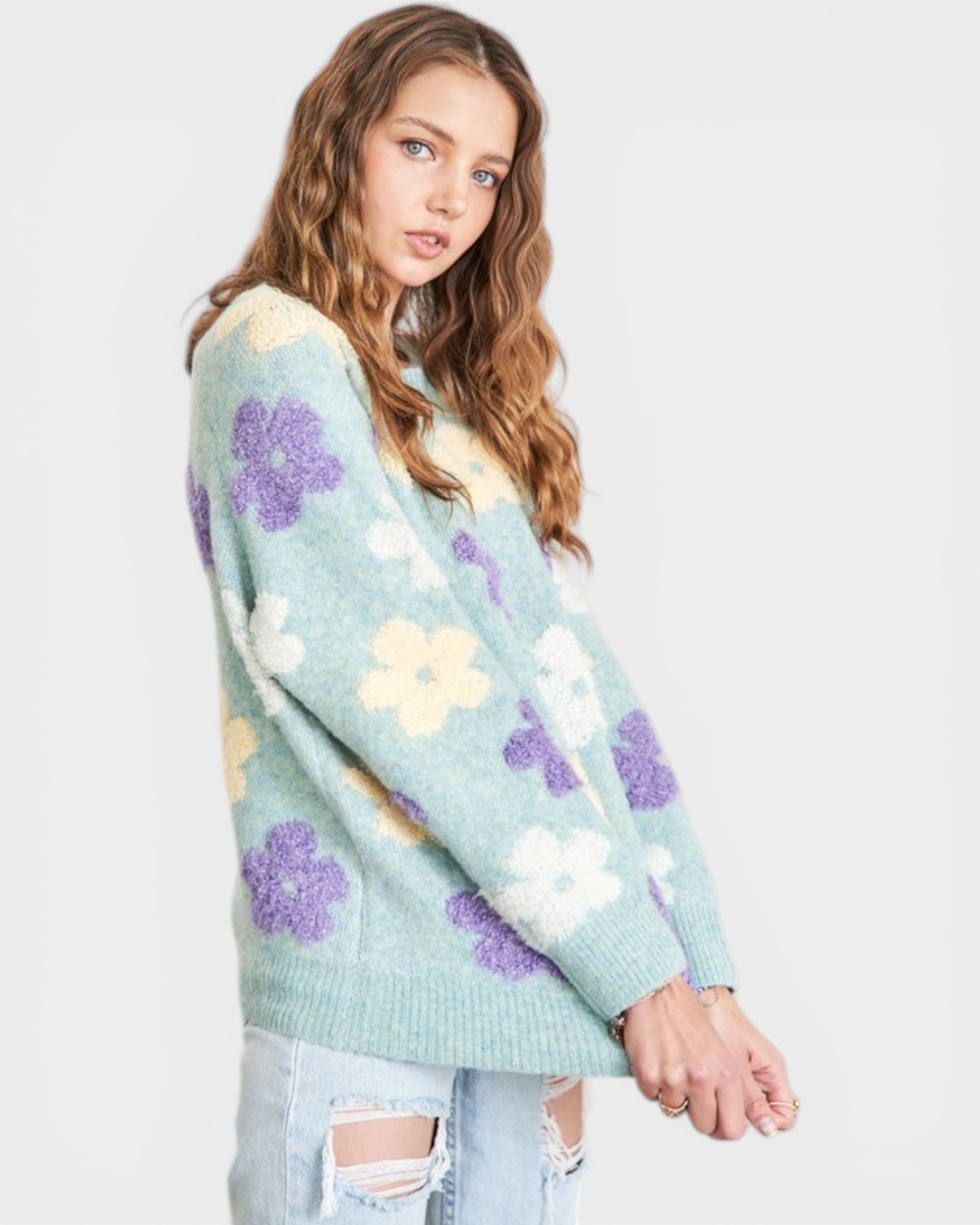 Woman wearing a light blue sweater with floral patterns on a white background