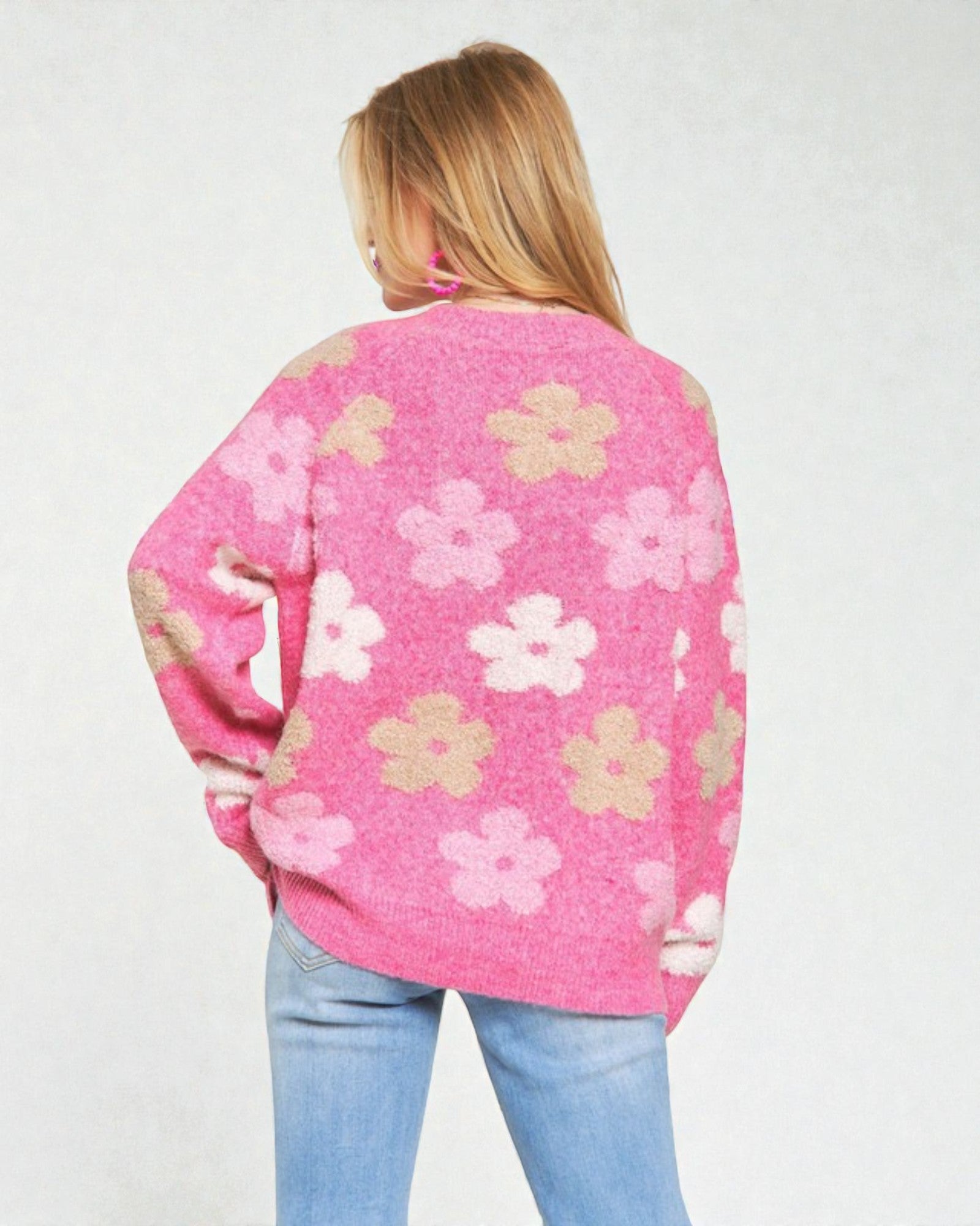Person wearing a pink floral-patterned sweater on a plain background