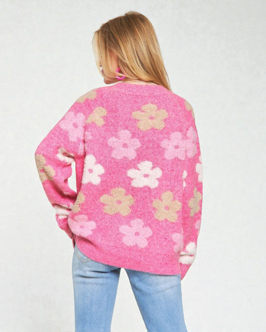 Person wearing a pink floral-patterned sweater on a plain background