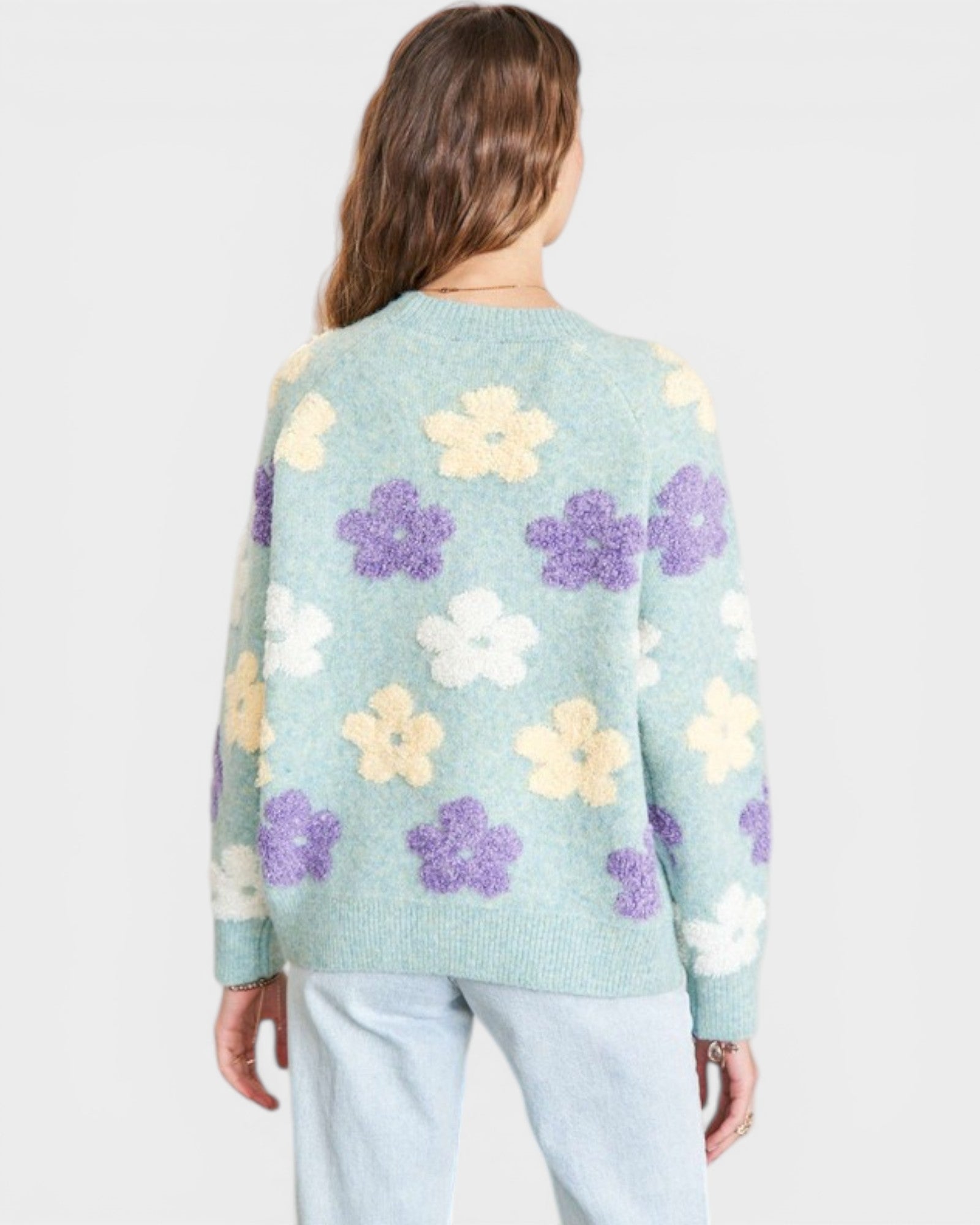 Light blue sweater with floral pattern worn by a person on a white background