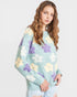 Woman wearing a light blue sweater with floral patterns on a plain background