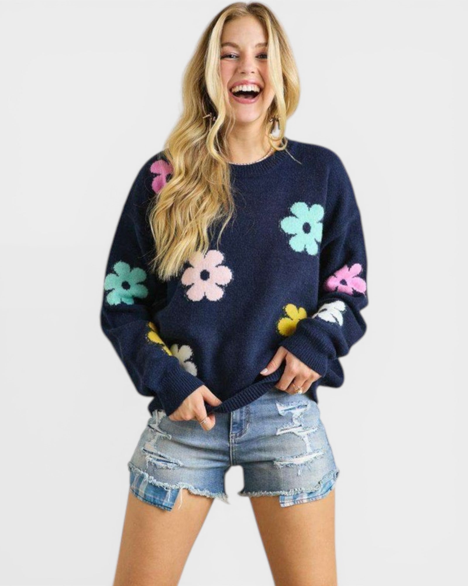 Woman wearing a navy sweater with colorful floral patterns on a white background