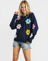 Woman wearing a navy sweater with colorful floral patterns on a white background