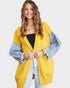 Woman wearing a yellow cardigan with blue sleeves on a white background