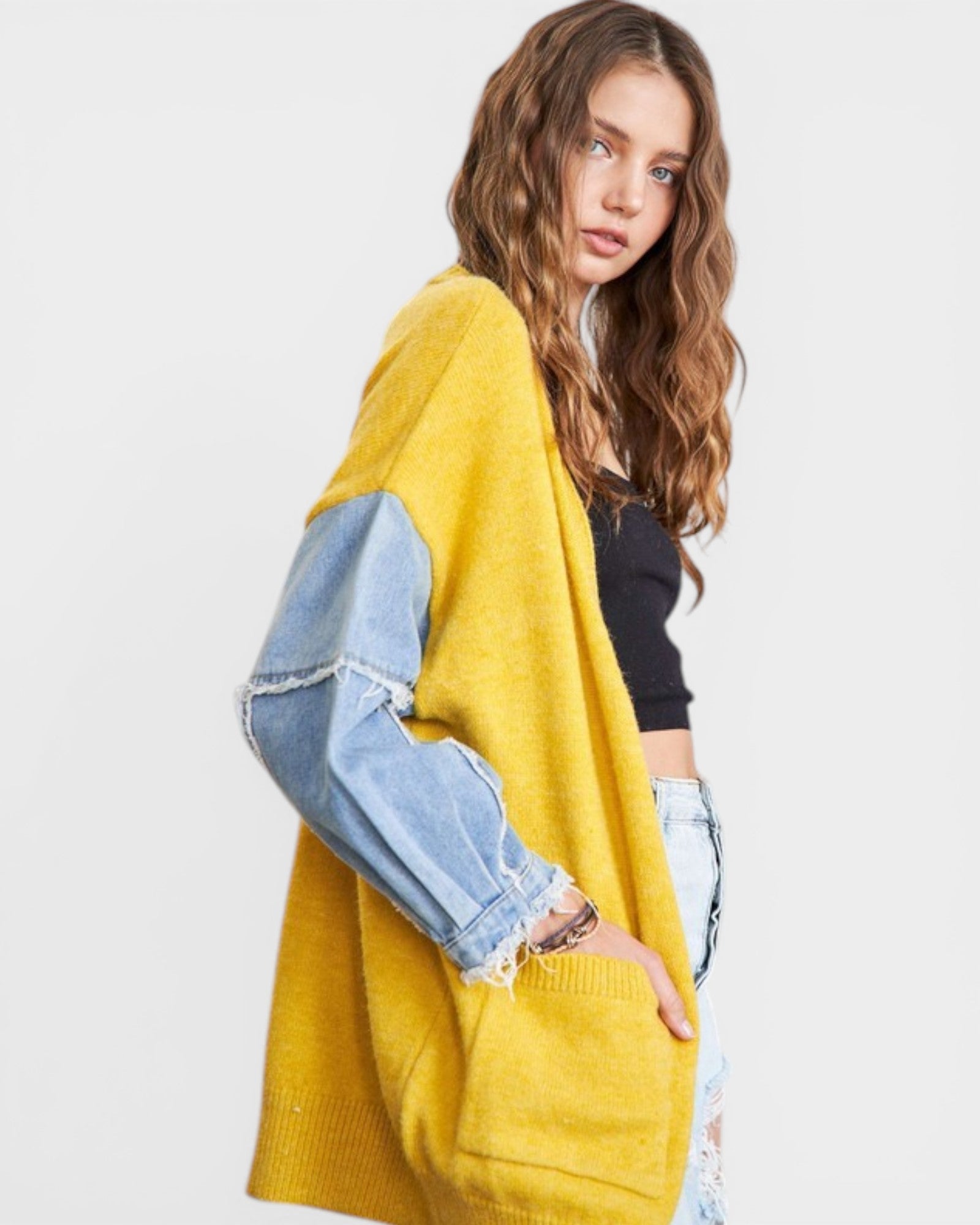 Woman wearing a yellow sweater with denim sleeves on a white background