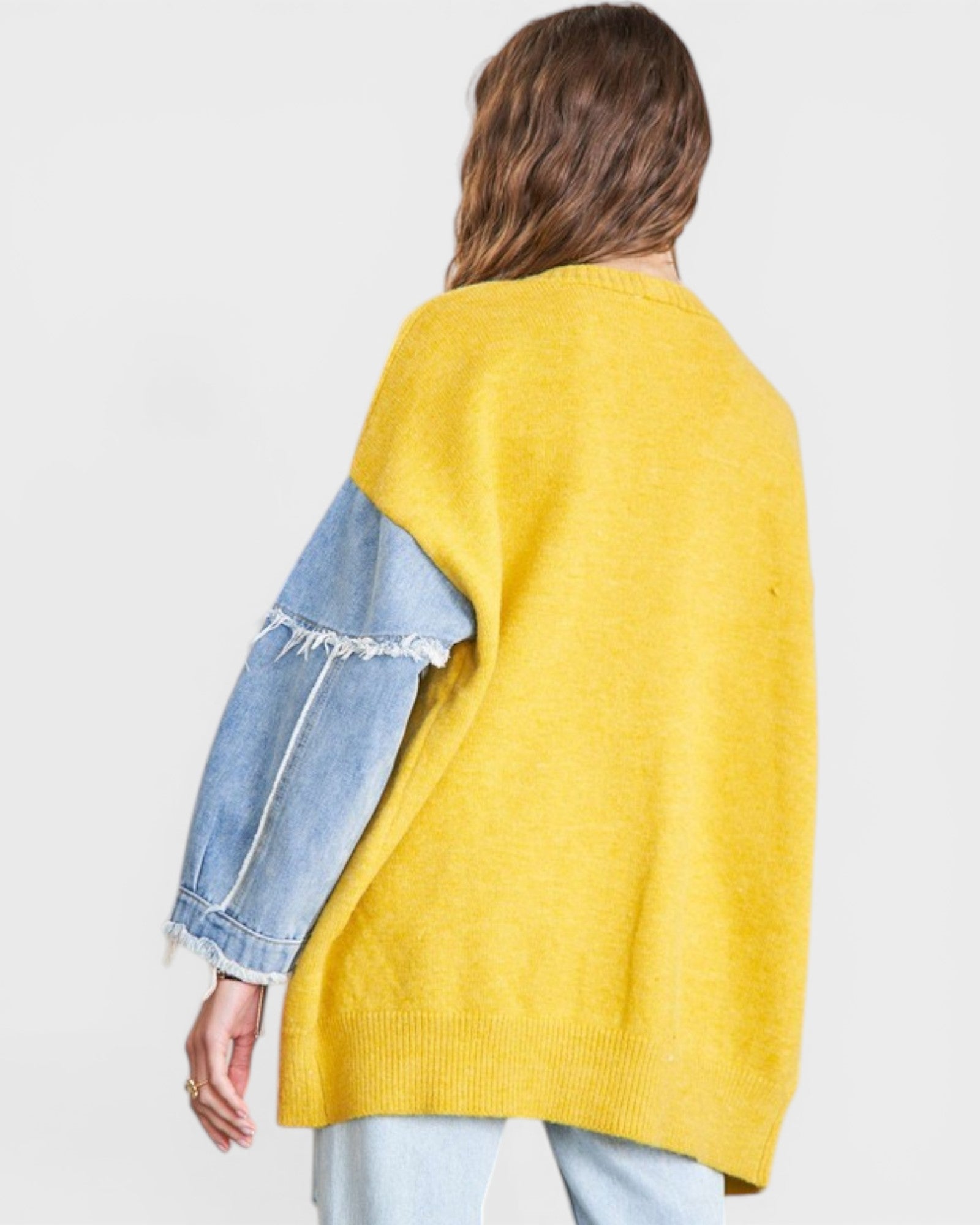 Person wearing a yellow sweater with denim sleeves on a white background