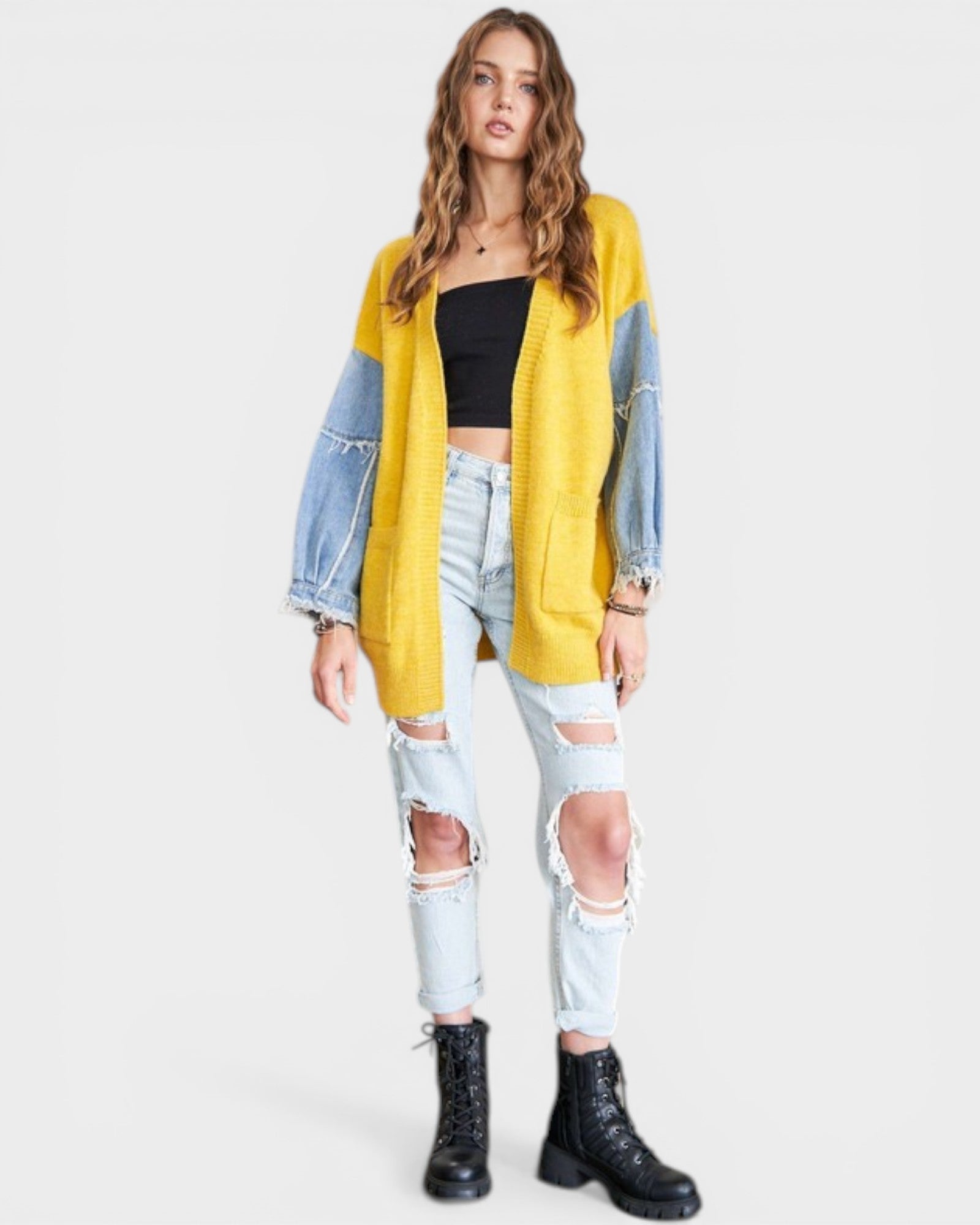 Woman wearing a yellow cardigan with denim sleeves on a white background