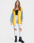 Woman wearing a yellow cardigan with denim sleeves on a white background