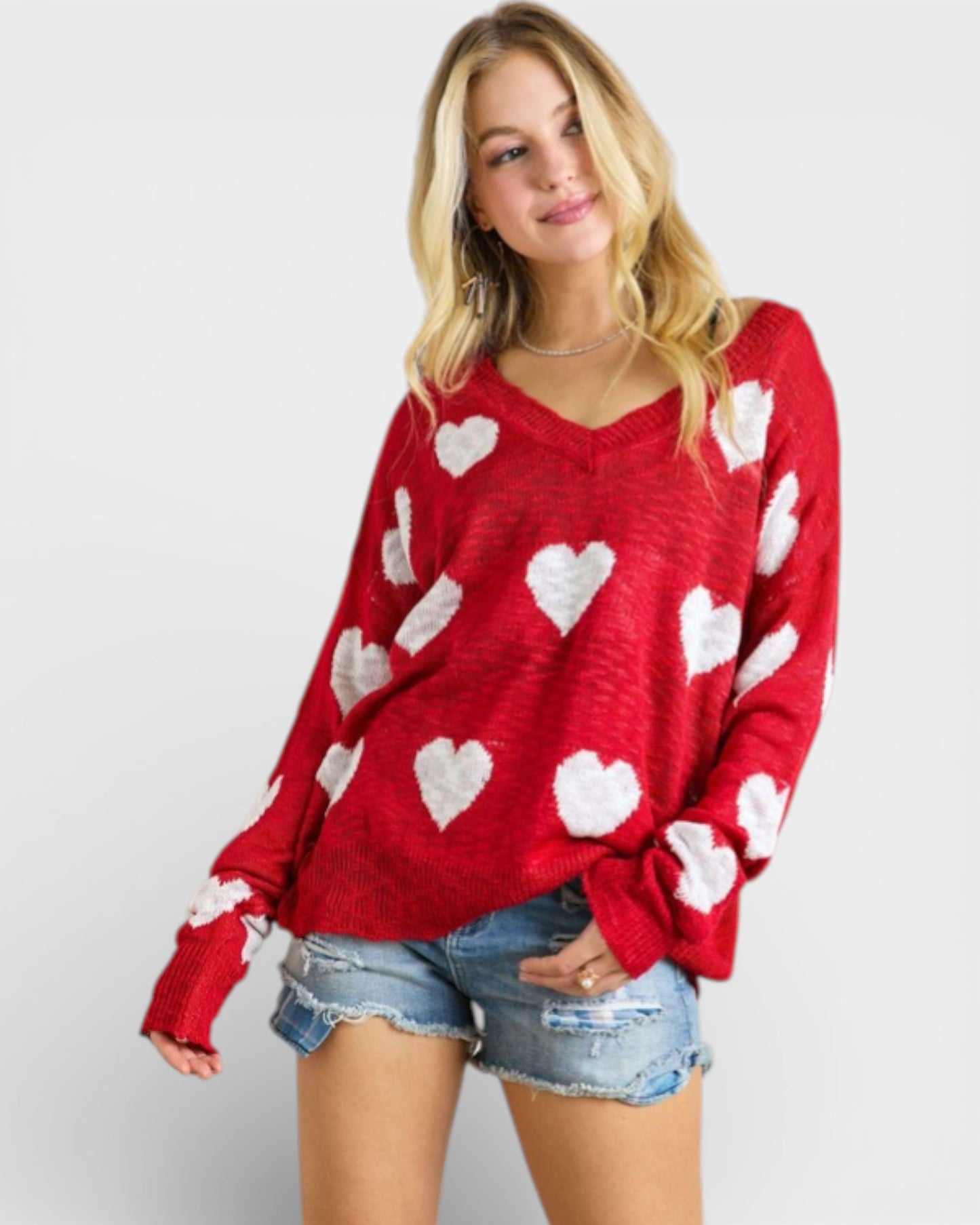 Woman wearing a red sweater with white heart patterns on a plain background