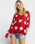 Woman wearing a red sweater with white heart patterns on a plain background