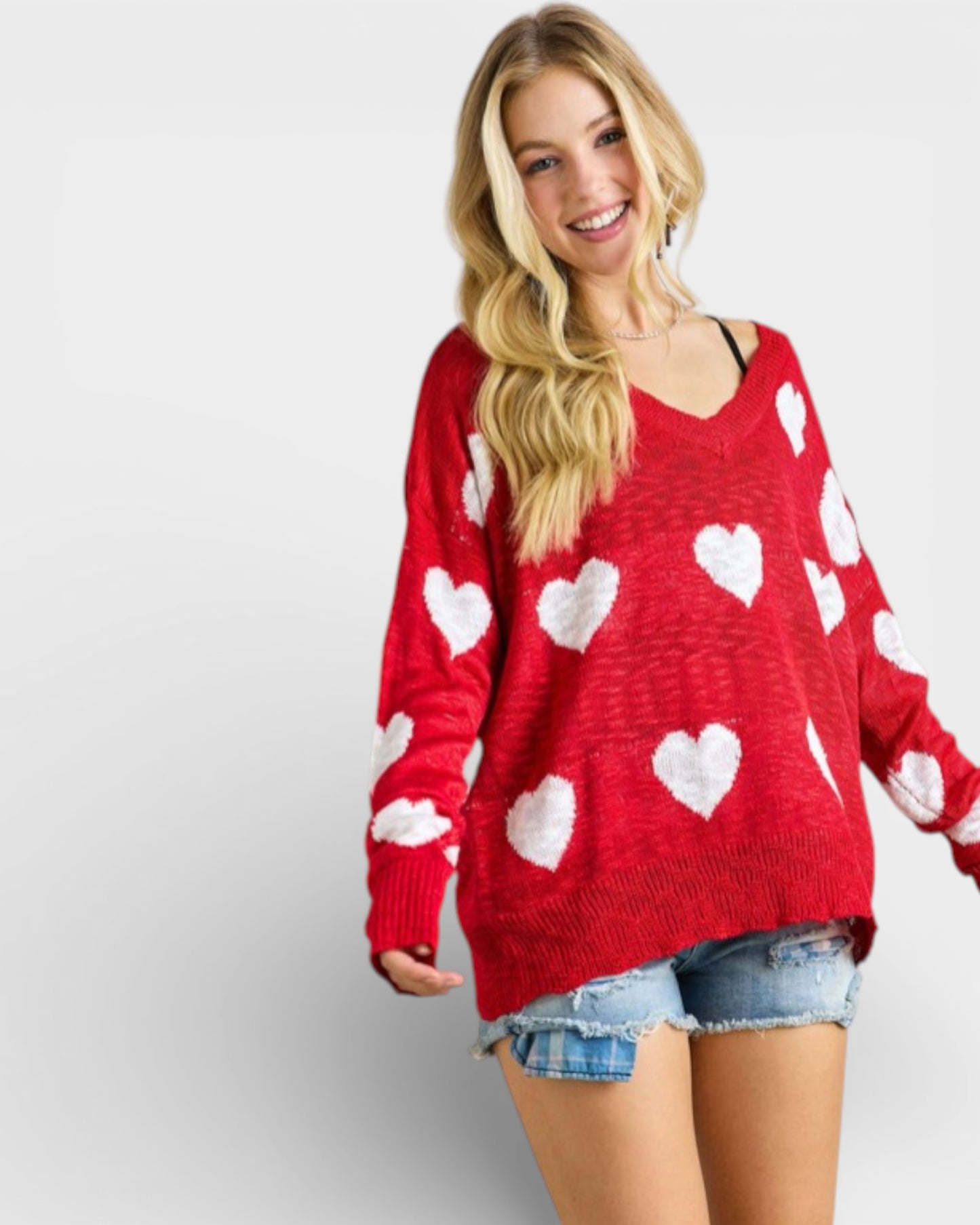 Woman wearing a red sweater with white heart patterns on a plain background