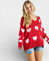 Woman wearing a red sweater with white heart patterns on a plain background