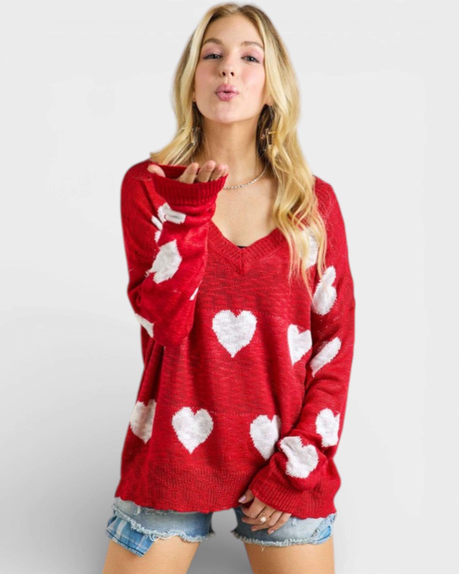Woman wearing a red sweater with white heart patterns on a plain background