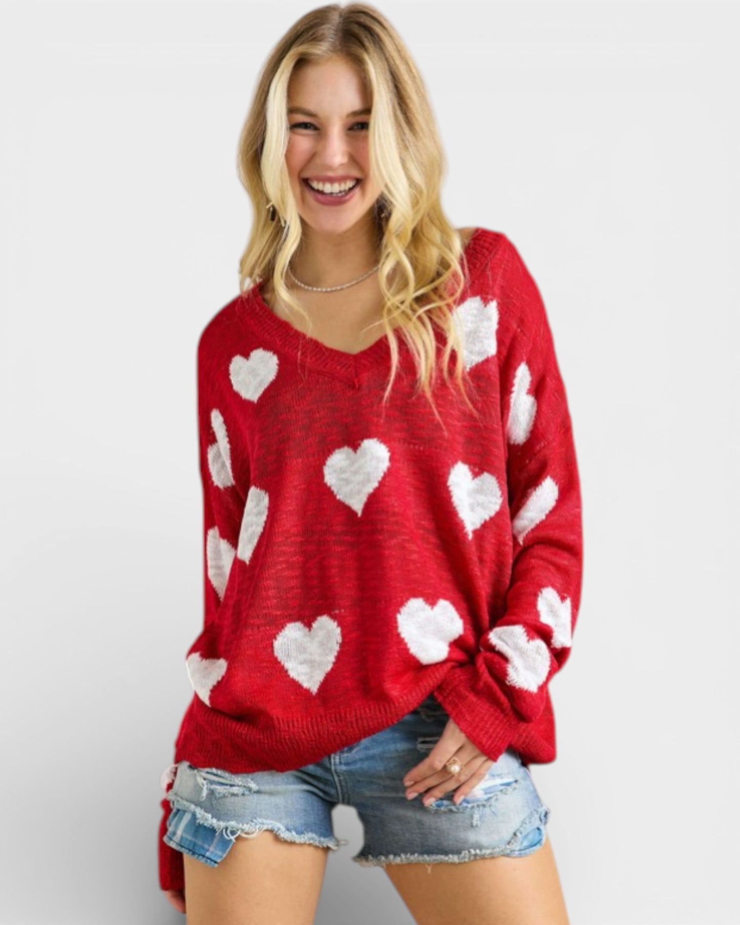 Woman wearing a red sweater with white heart patterns on a plain background