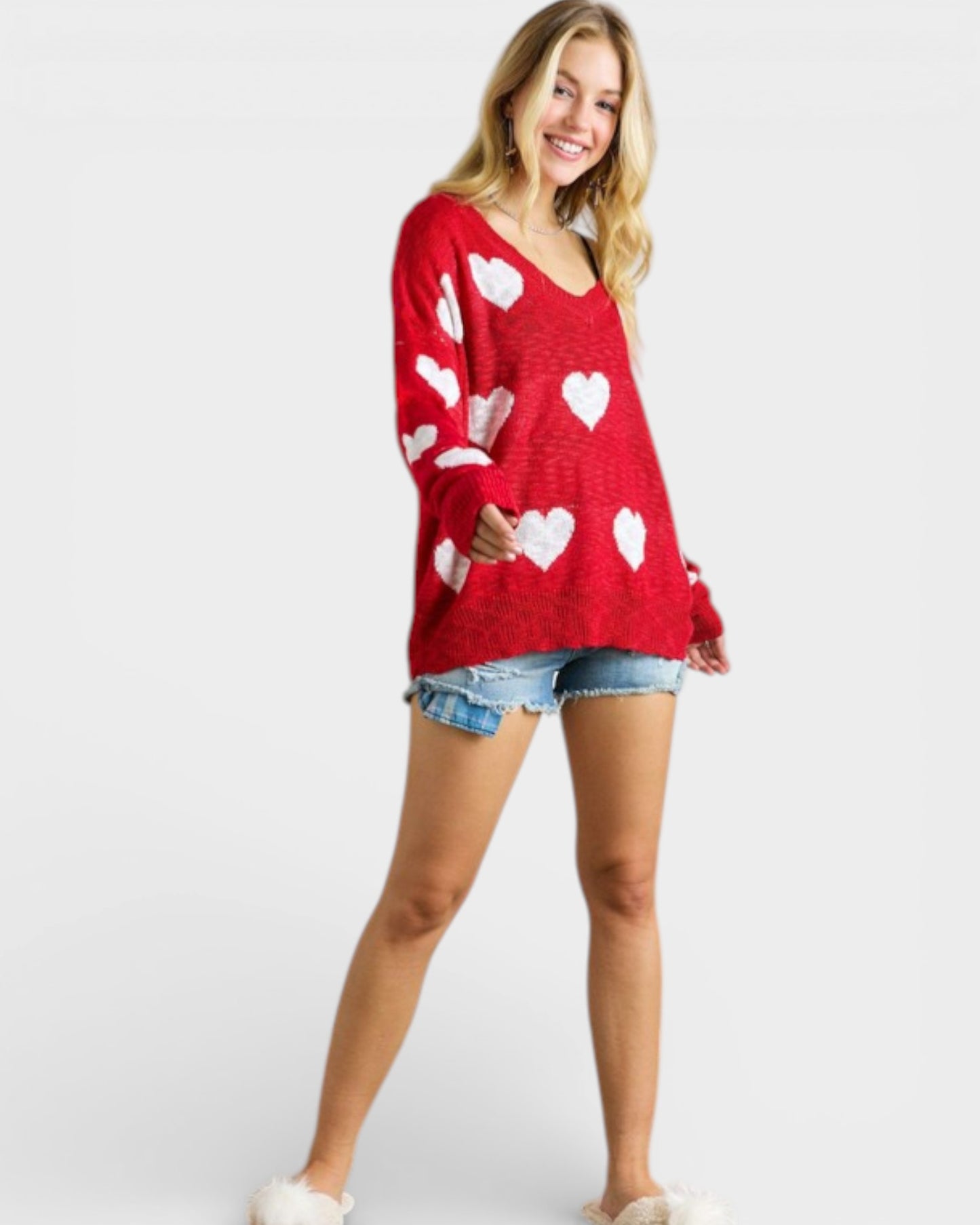 Woman wearing a red sweater with white heart patterns on a plain background
