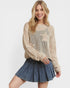 Woman wearing a beige knit sweater with star patterns and a denim skirt on a white background