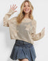 Woman wearing a beige knit sweater and denim skirt on a white background