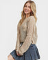 Woman wearing a beige knit sweater and denim skirt on a white background