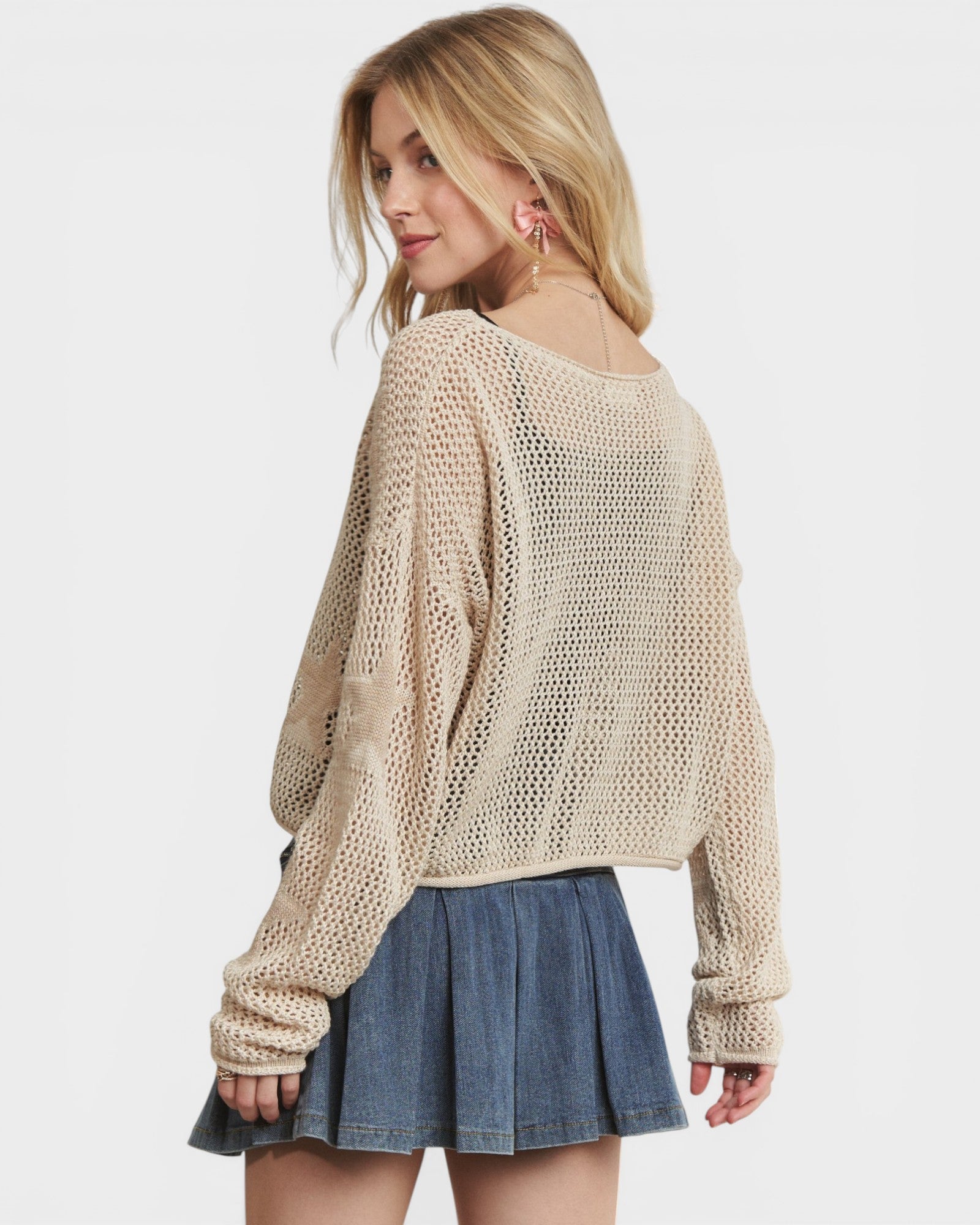 Woman wearing a beige knitted sweater and denim skirt on a white background