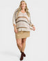 Woman wearing a striped sweater and beige skirt on a white background