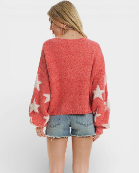Person wearing a red sweater with star patterns and denim shorts on a white background