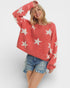 Woman wearing a red sweater with white star patterns on a plain background