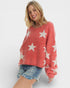 Woman wearing a red sweater with white star patterns on a plain background