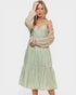 Woman wearing a green checkered dress with a beige sweater on a white background