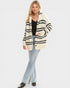 Woman wearing a striped cardigan, black top, and light blue jeans on a white background