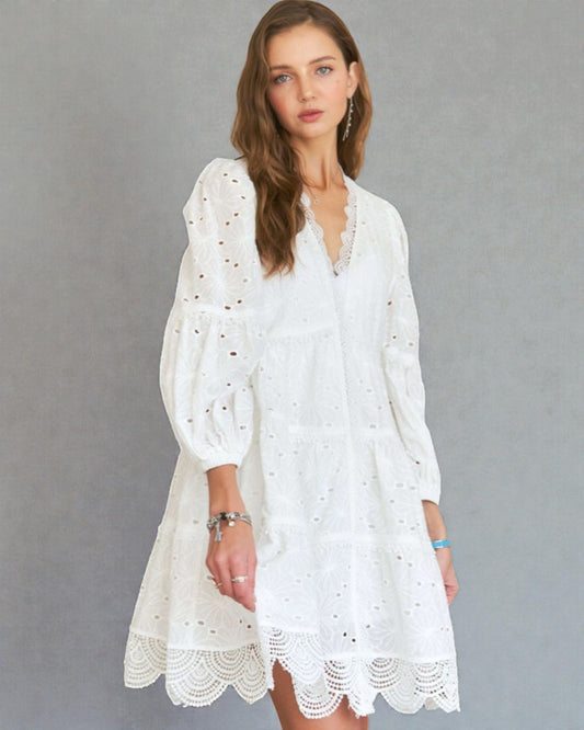 Woman wearing a white lace dress against a gray background