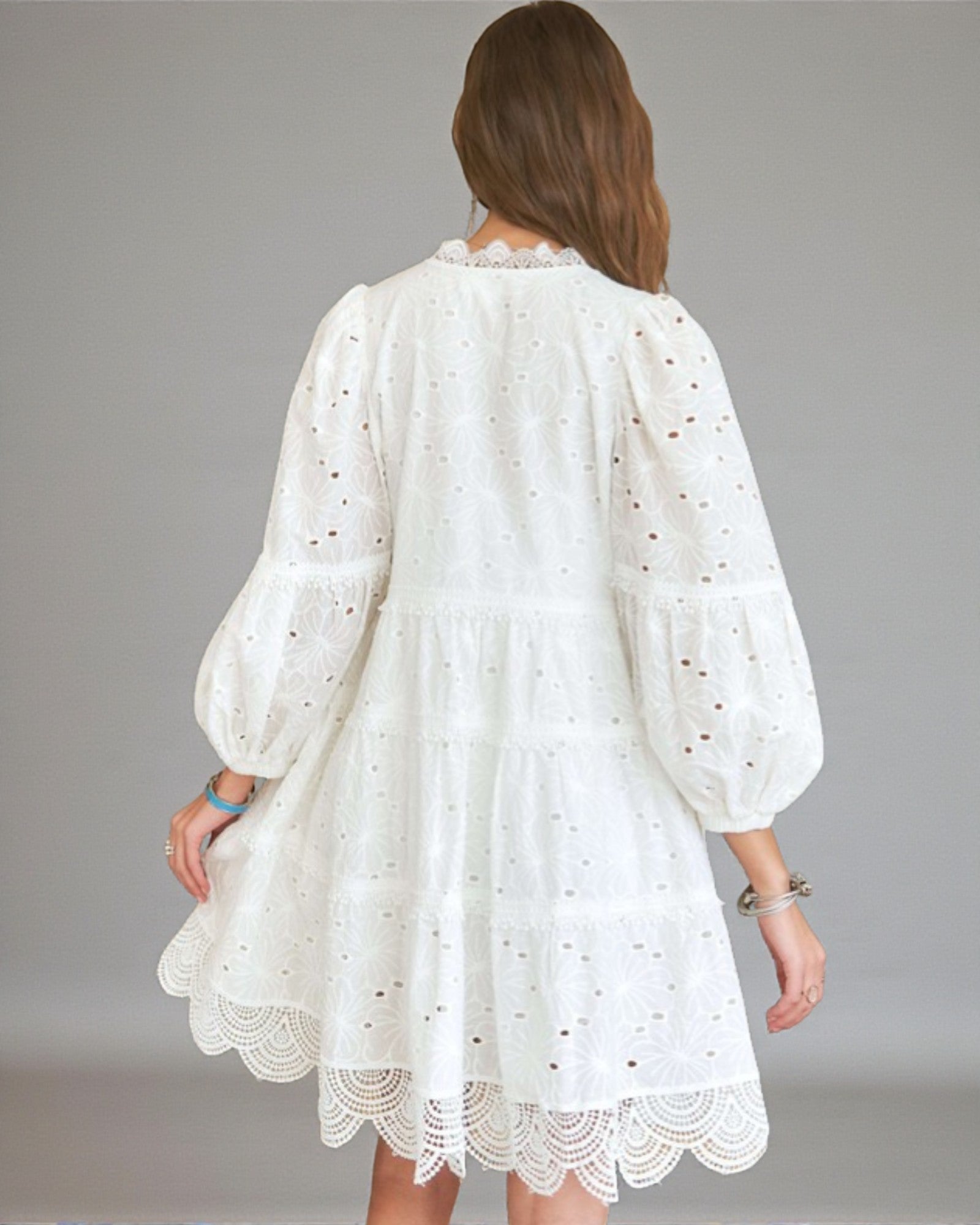 White lace dress worn by a person on a gray background