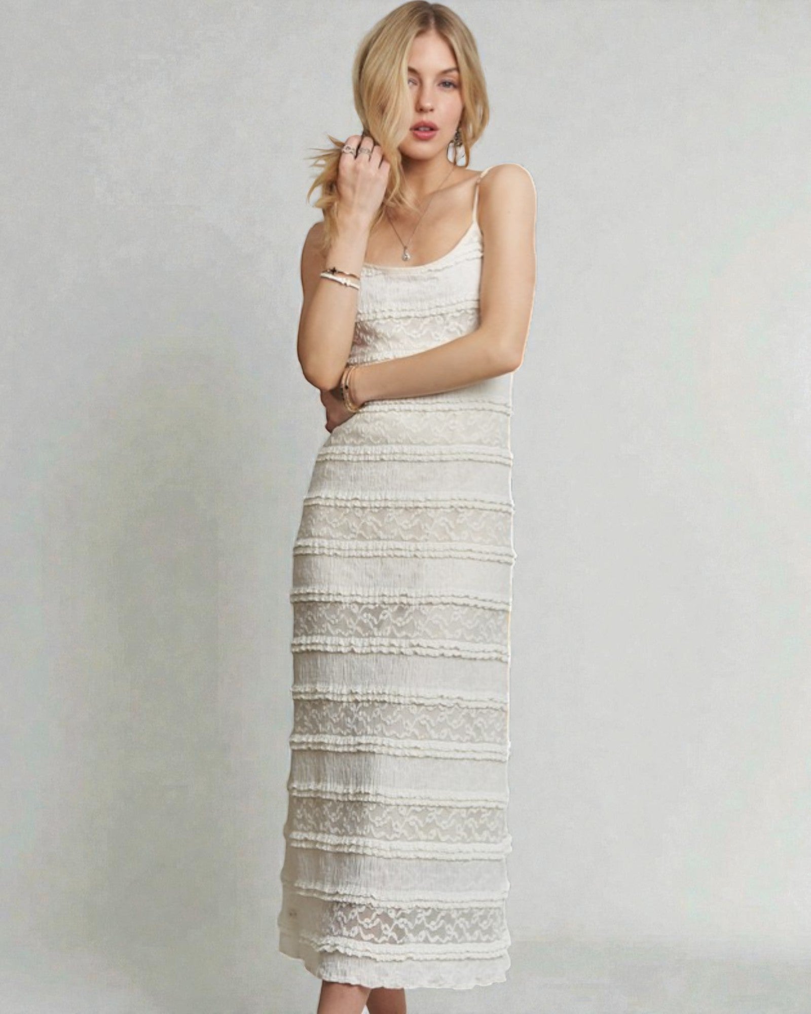 Woman wearing a white lace dress against a plain background