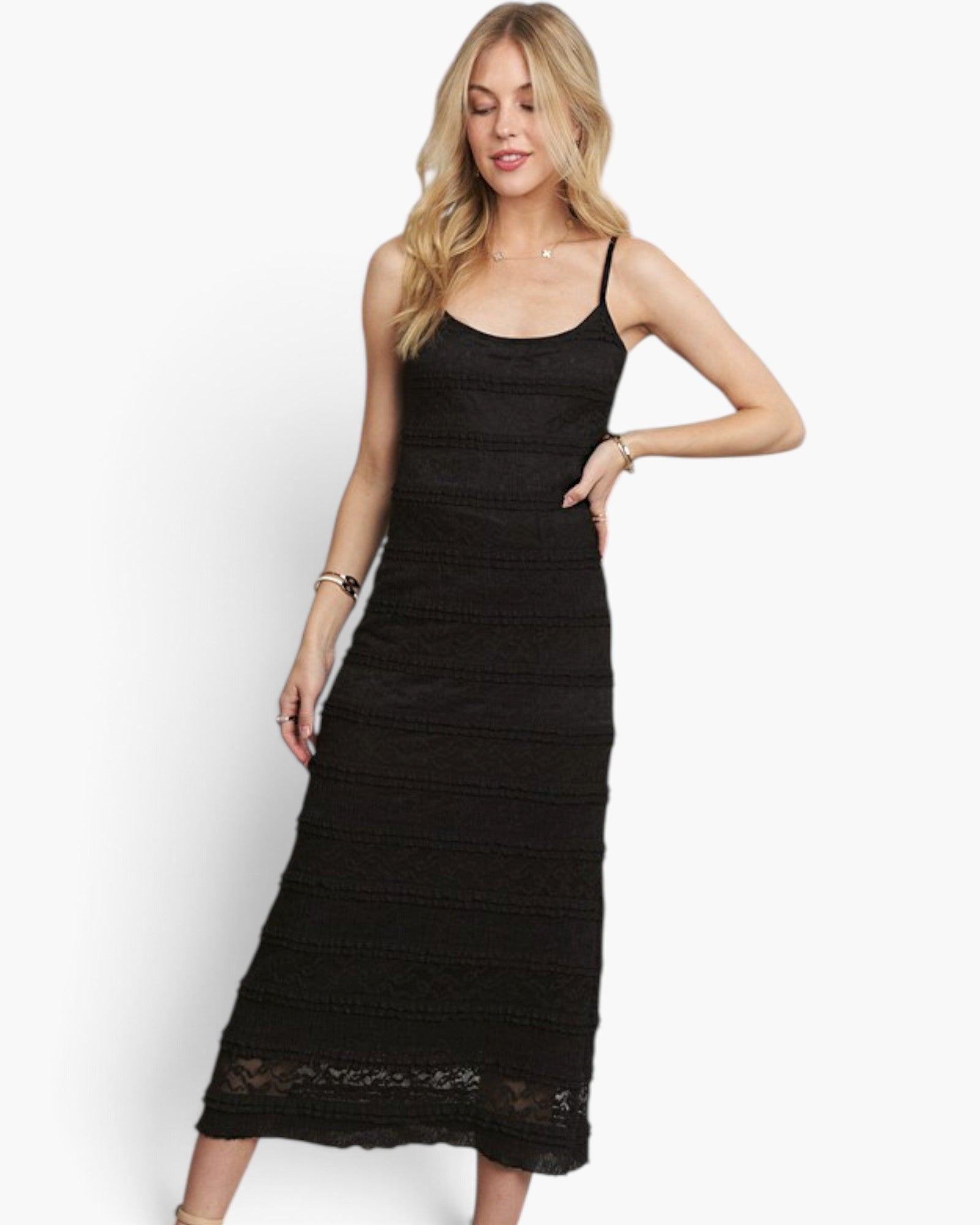 A blonde model wearing a black lace spaghetti-strap midi dress against a plain white studio background.