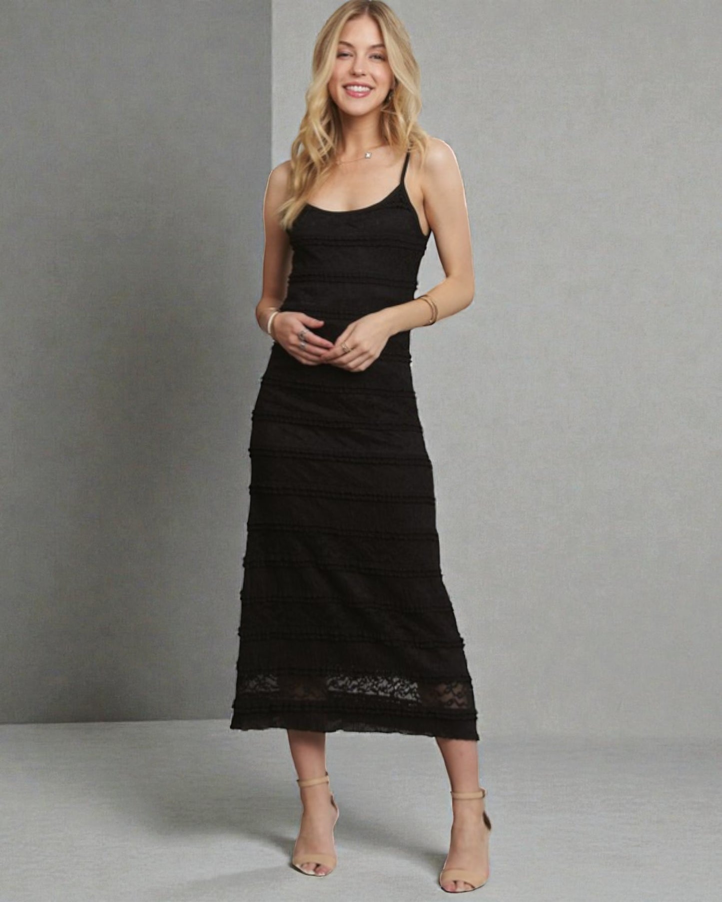 Woman wearing a black dress with lace details against a gray background