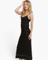 A woman modeling a black sleeveless midi dress with thin straps and a textured, tiered lace-like skirt against a plain white studio background.