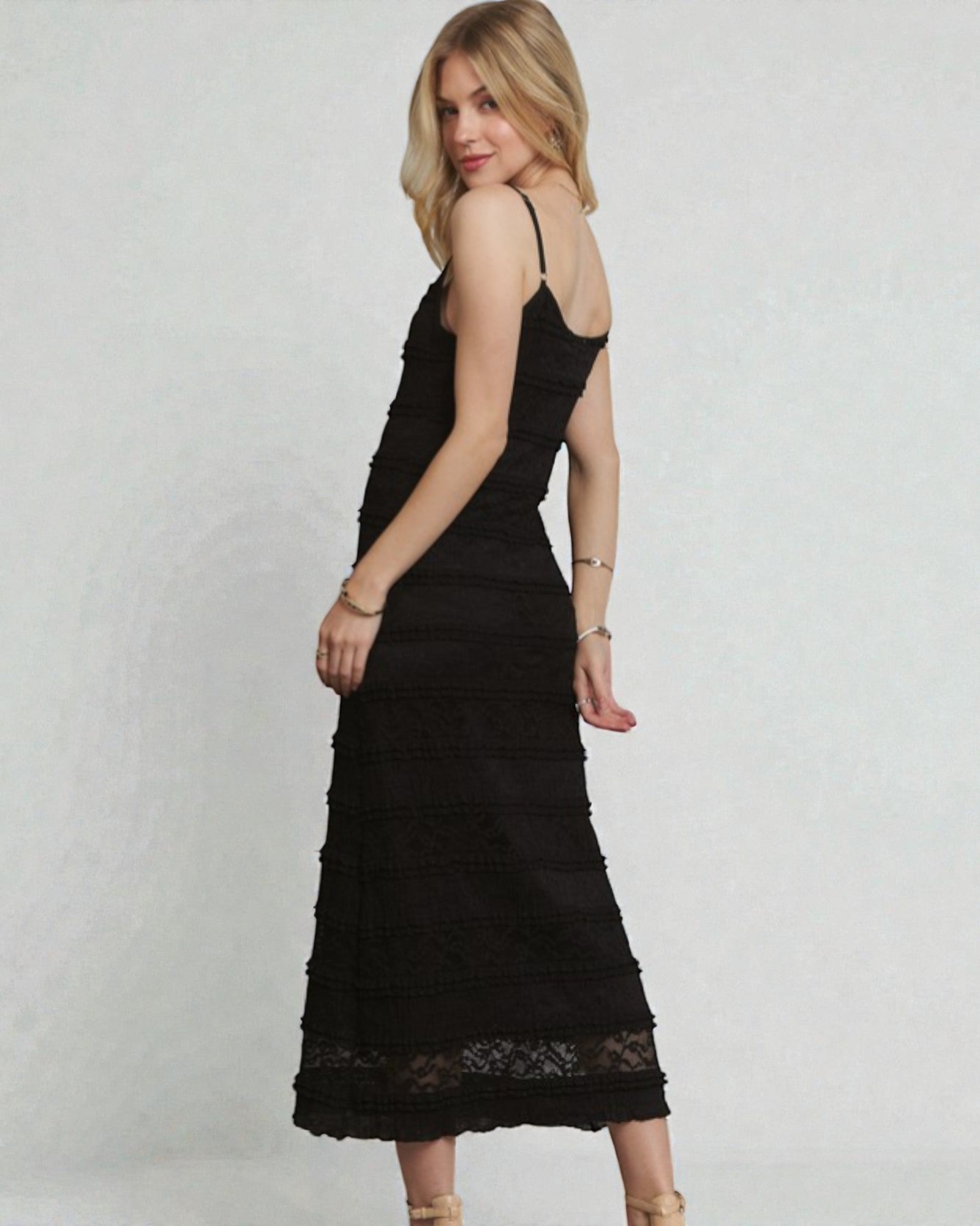 Woman wearing a black lace dress against a plain background