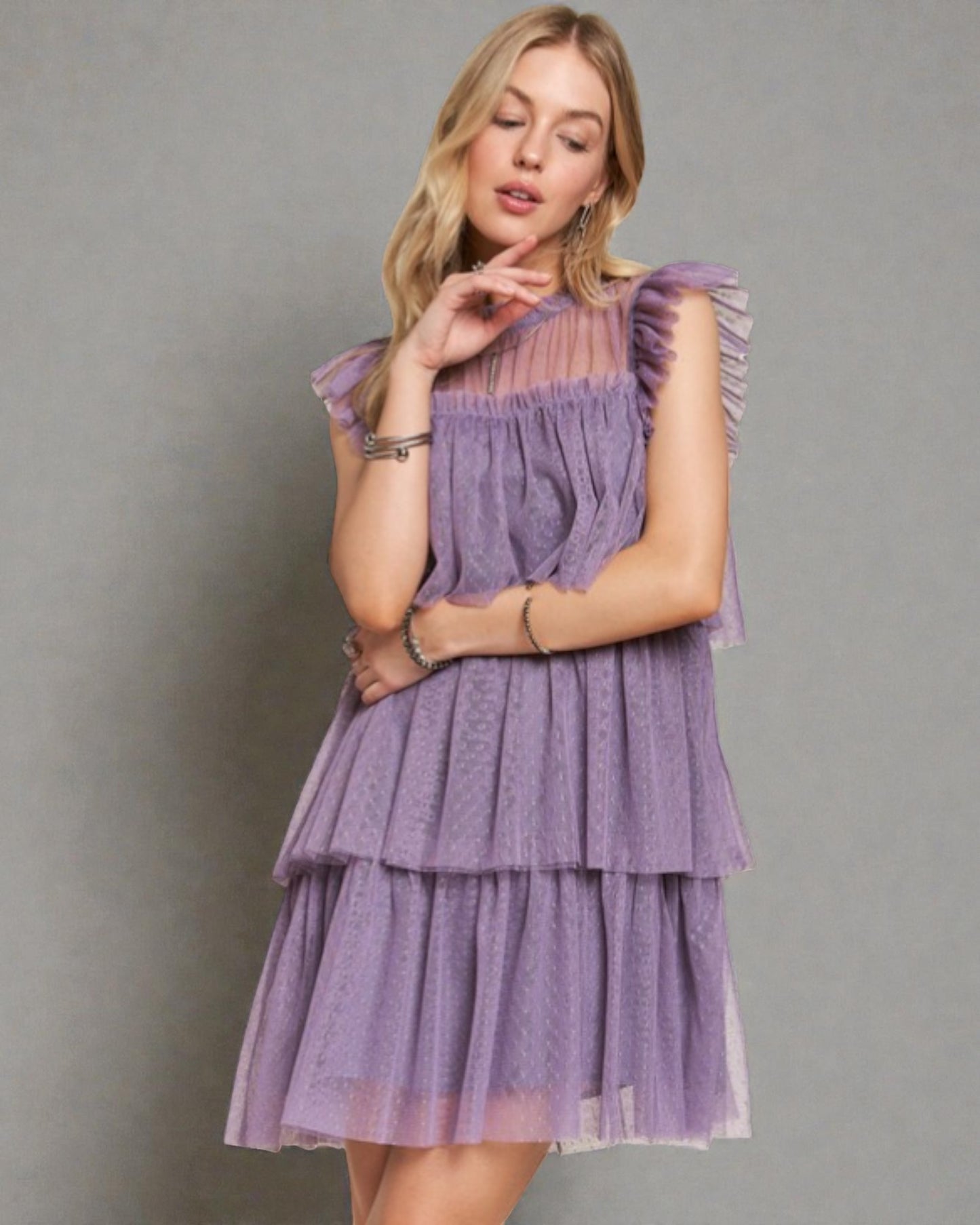 Woman wearing a purple tiered dress against a gray background