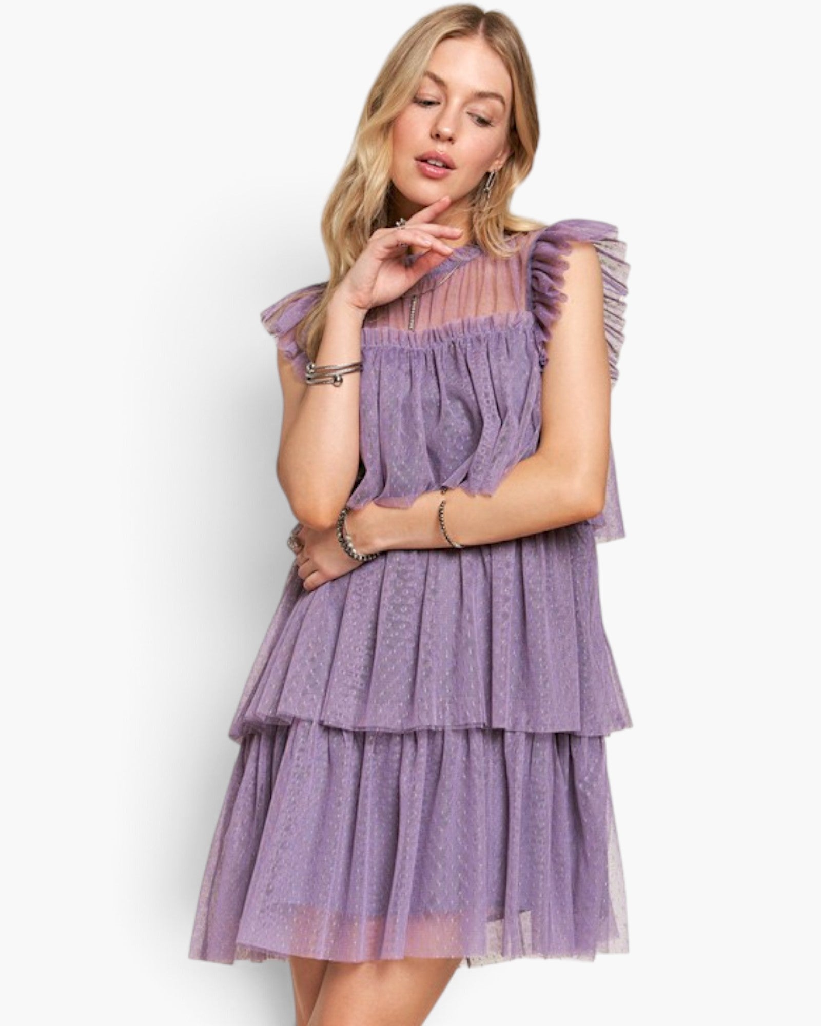 A woman modeling a lavender purple tiered tulle dress with ruffled cap sleeves against a plain white studio background.