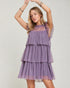 Woman wearing a purple tiered dress against a plain background