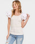 Woman wearing a white top with ruffled sleeves and blue jeans on a plain background