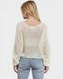 Woman wearing a beige mesh top and light blue jeans on a white background