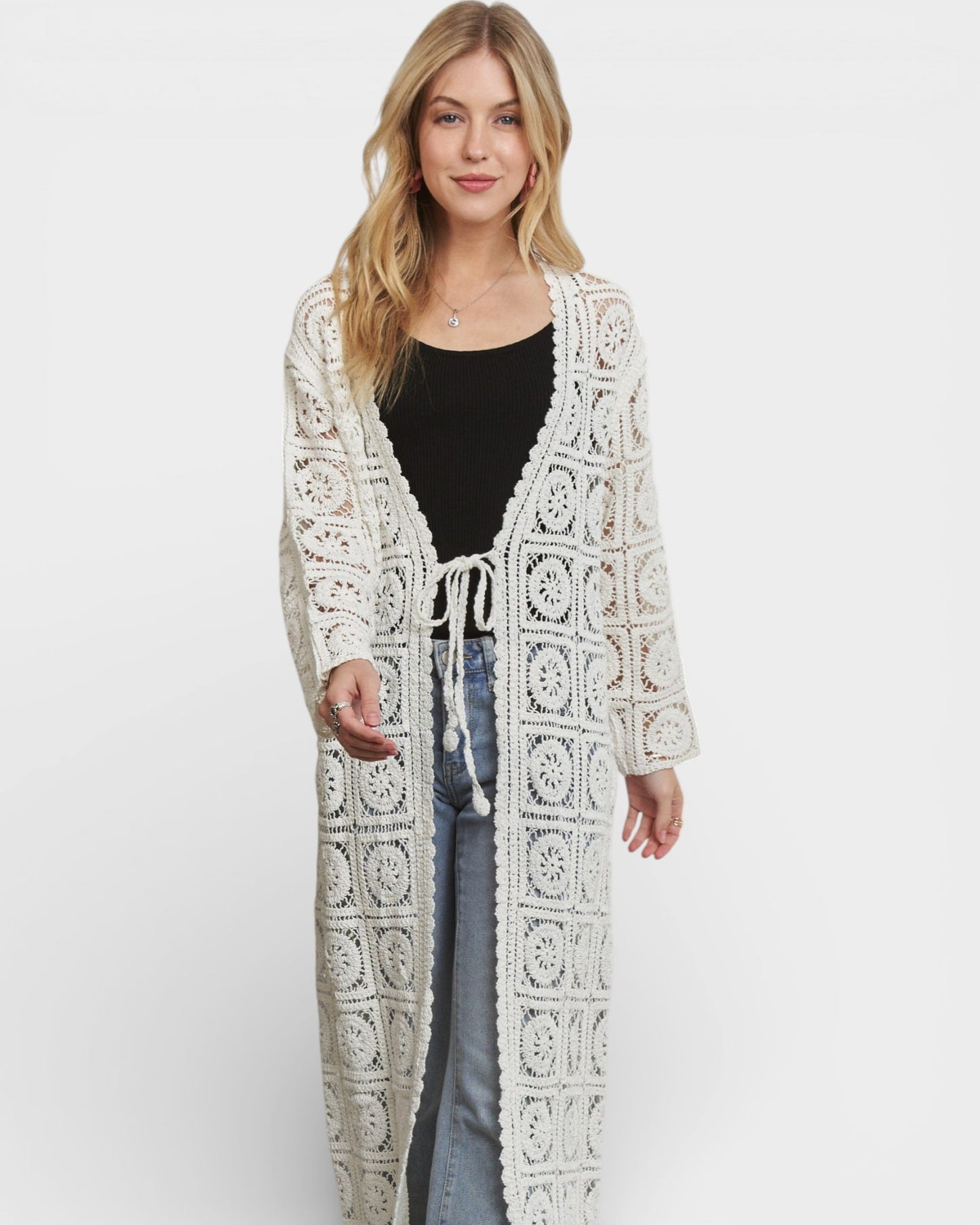 Woman wearing a long, patterned white cardigan on a white background