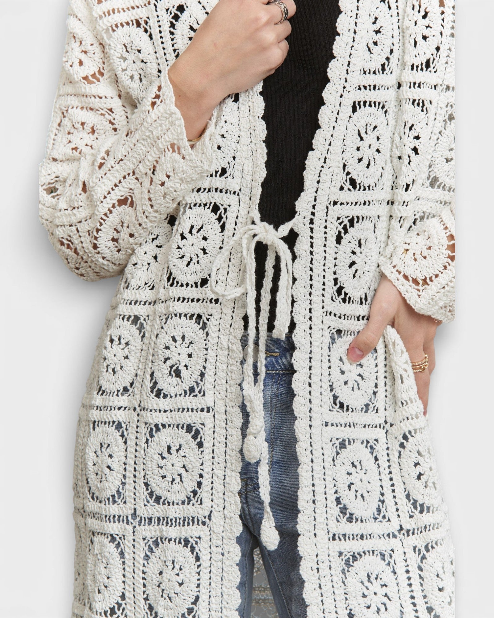 White crochet cardigan worn by a person on a white background