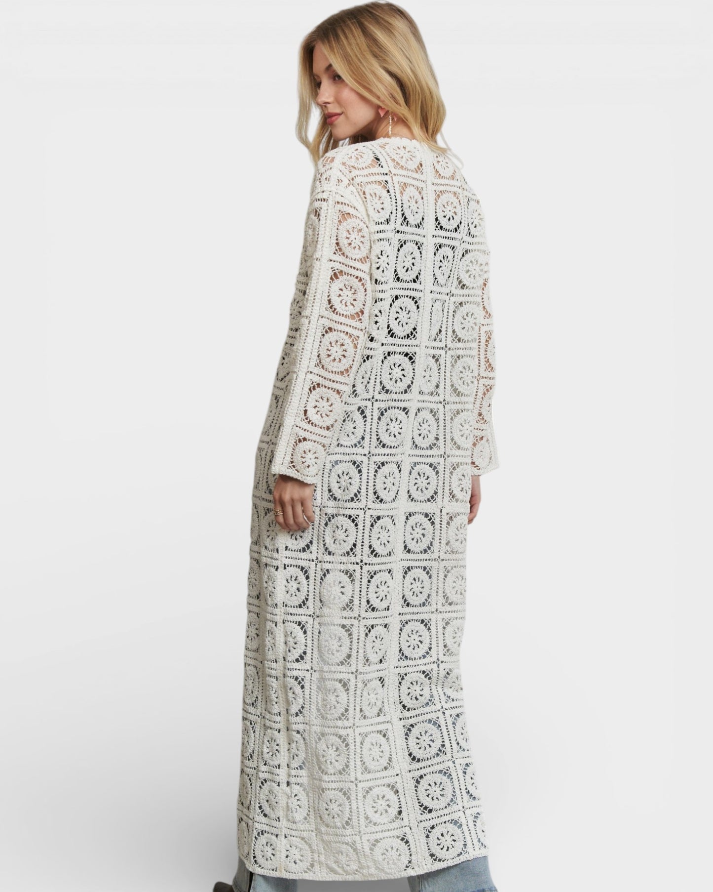 Woman wearing a long, patterned coat against a white background
